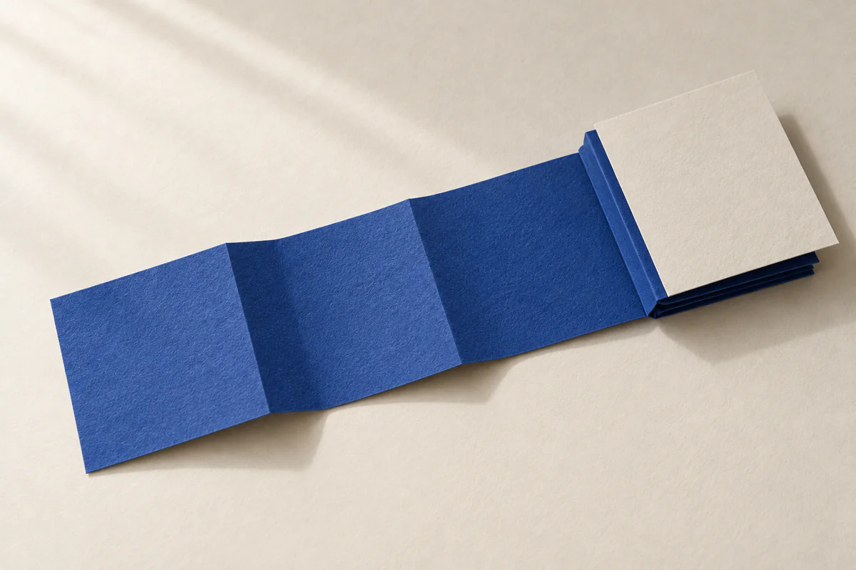 Ein langer blauer Papierstreifen ist mehrfach gefaltet. Die ersten drei Abschnitte liegen offen, der Rest bildet einen Stapel unter einem weißen Blatt.